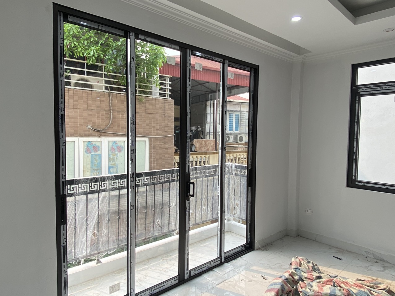 Cửa nhôm kính trượt lớn mở ra ban công, khung màu đen lắp trong phòng khách mới xây